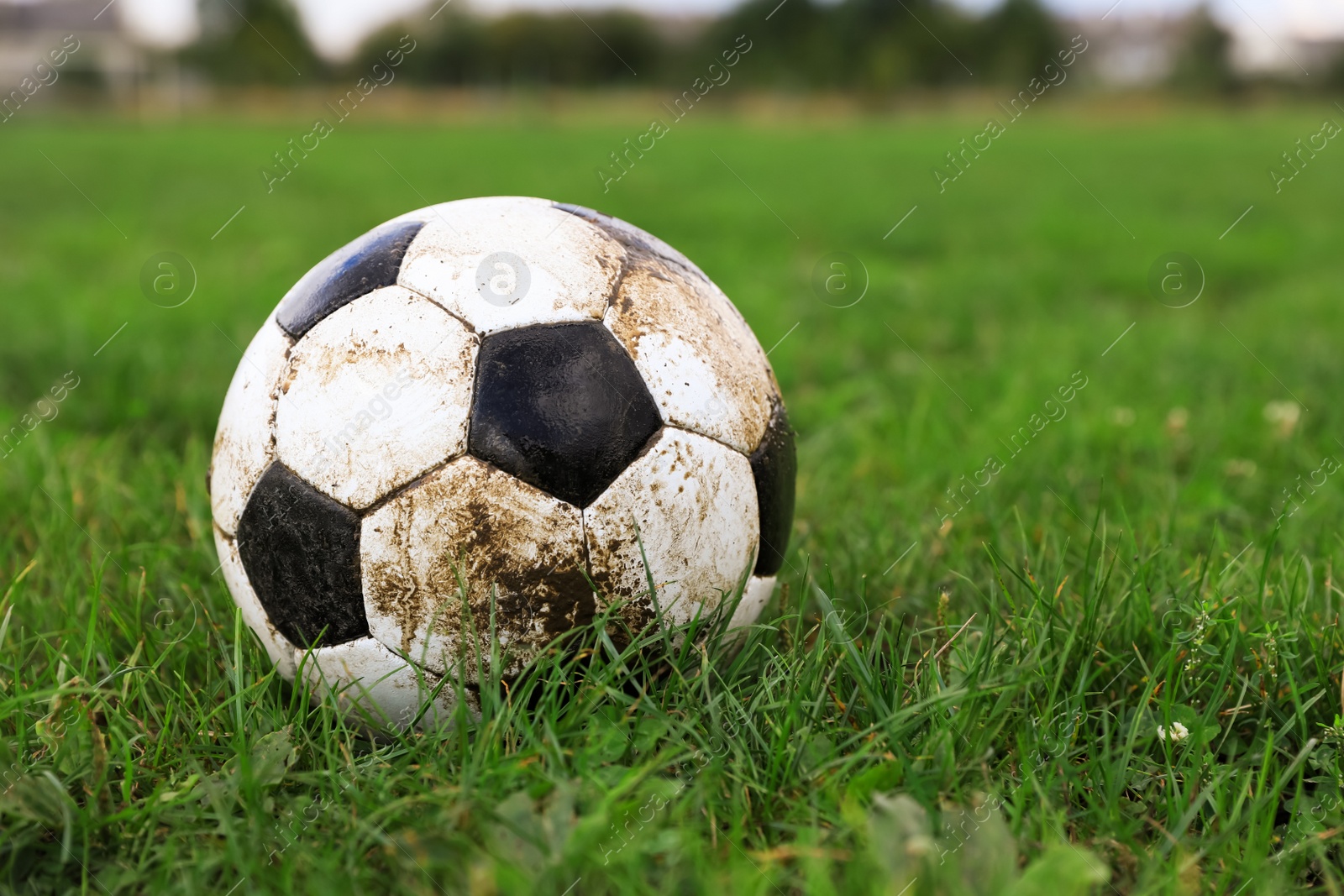 Photo of Dirty soccer ball on green grass outdoors, space for text