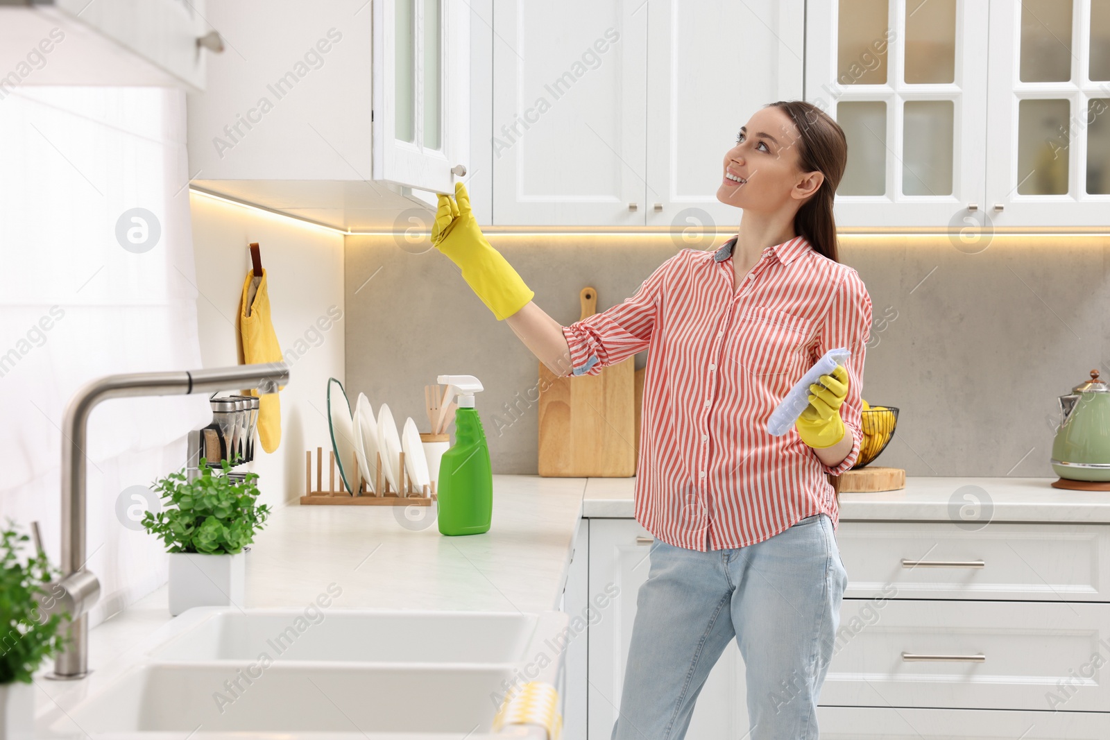 Photo of Spring cleaning. Young woman tidying up kitchen at home