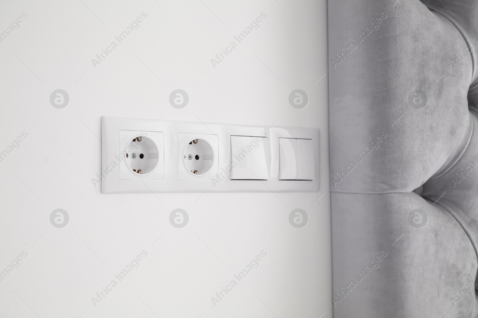 Photo of Light switches and power sockets on white wall indoors