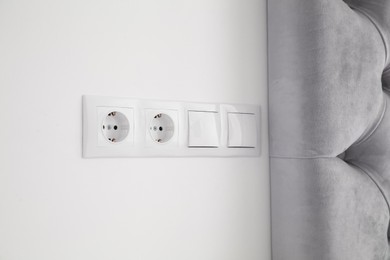 Photo of Light switches and power sockets on white wall indoors