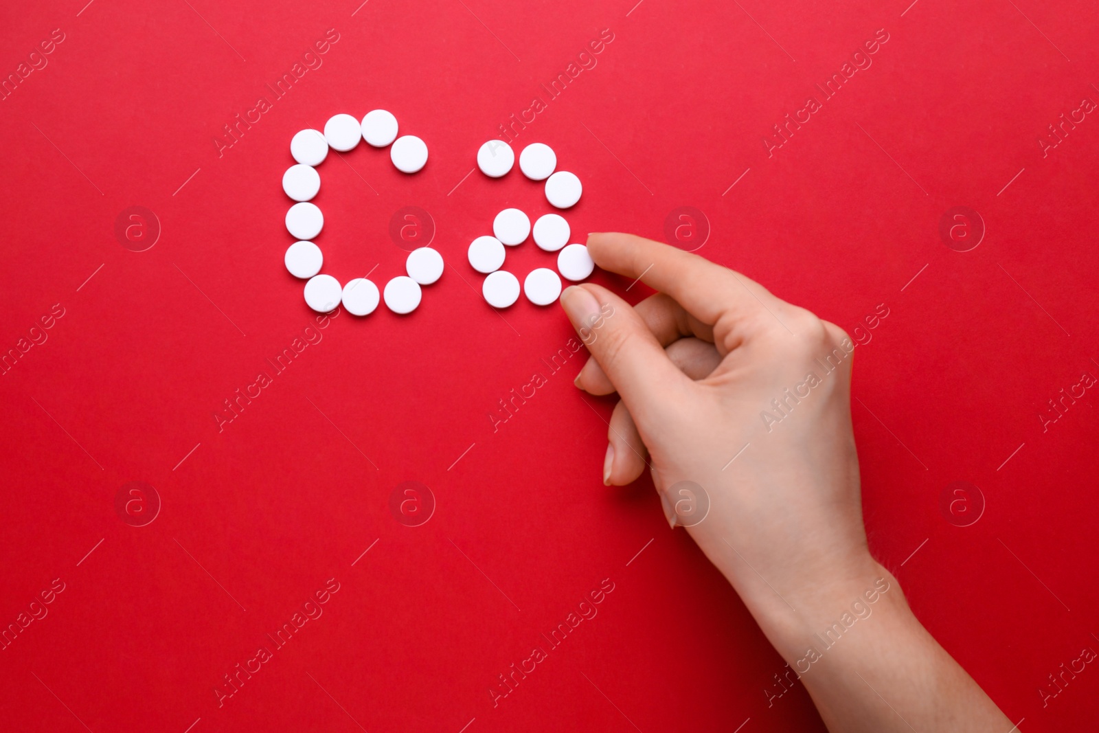 Photo of Woman making calcium symbol with white pills on red background, top view
