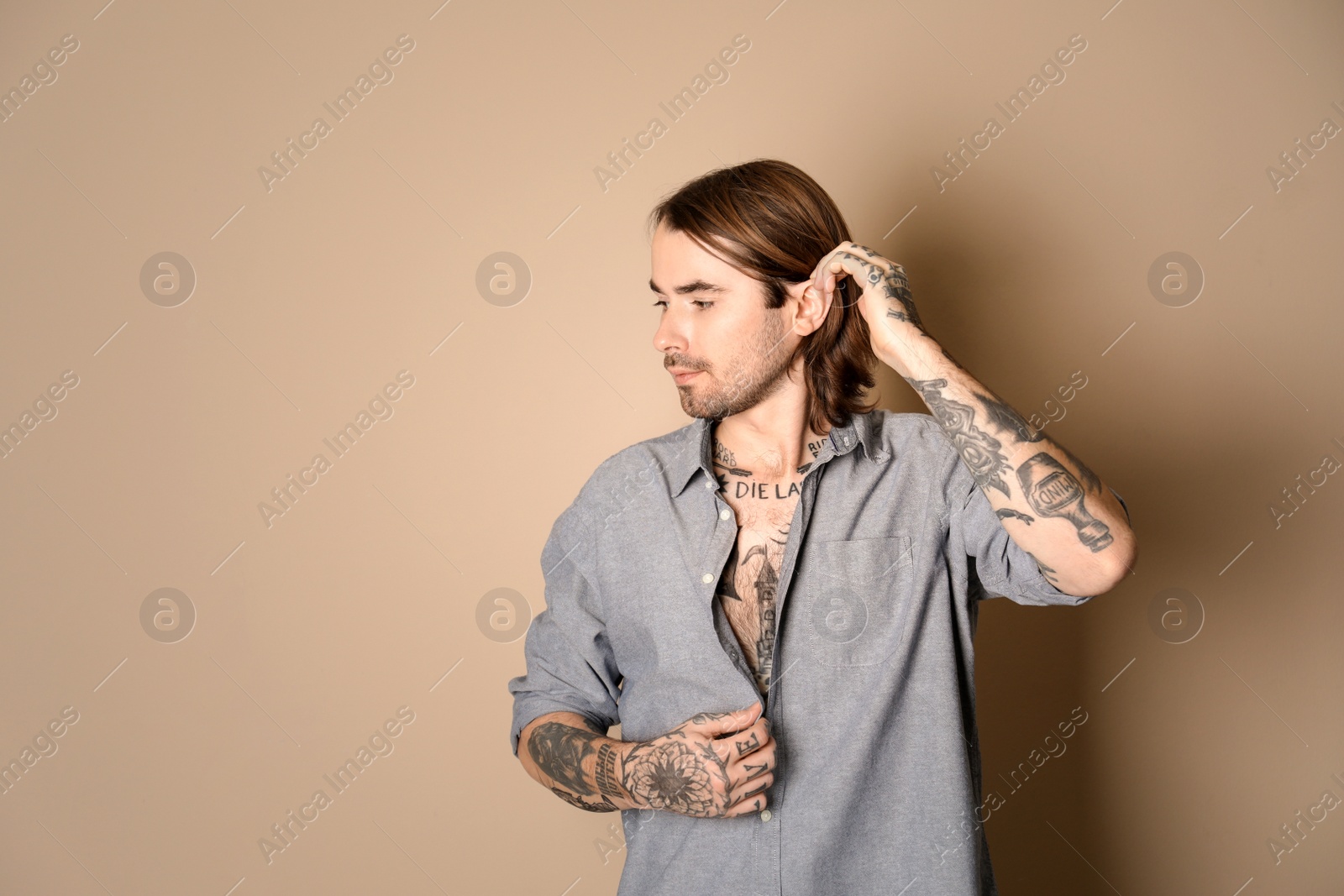 Photo of Young man with tattoos on body against beige background. Space for text