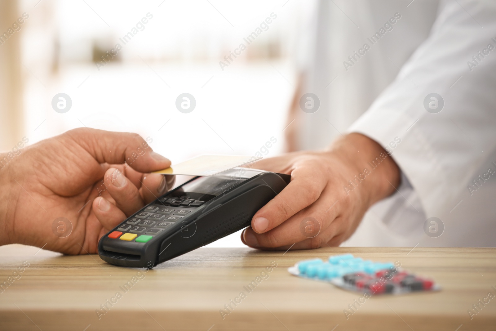 Photo of Customer using terminal for contactless payment with credit card in pharmacy, closeup