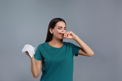 Photo of Young woman suffering from allergy on grey background