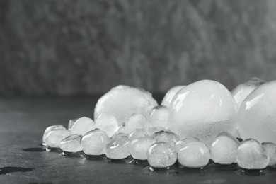 Photo of Many melting ice balls on dark table, space for text
