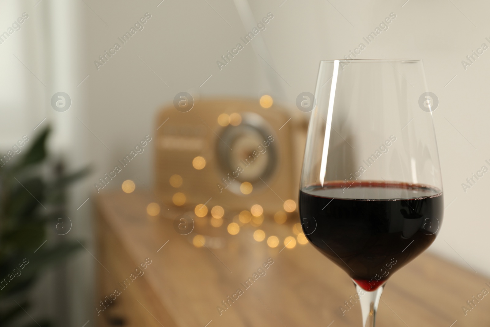 Photo of Relax at home. Glass of red wine in room, closeup. Space for text