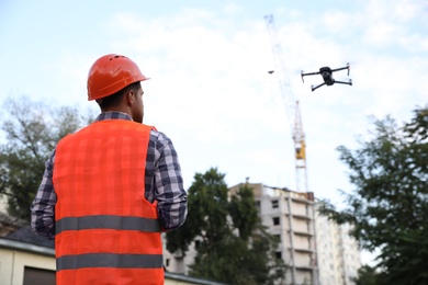 Photo of Builder operating drone with remote control at construction site. Aerial survey