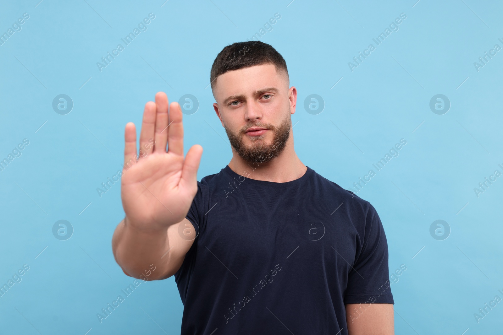 Photo of Man showing stop gesture on light blue background