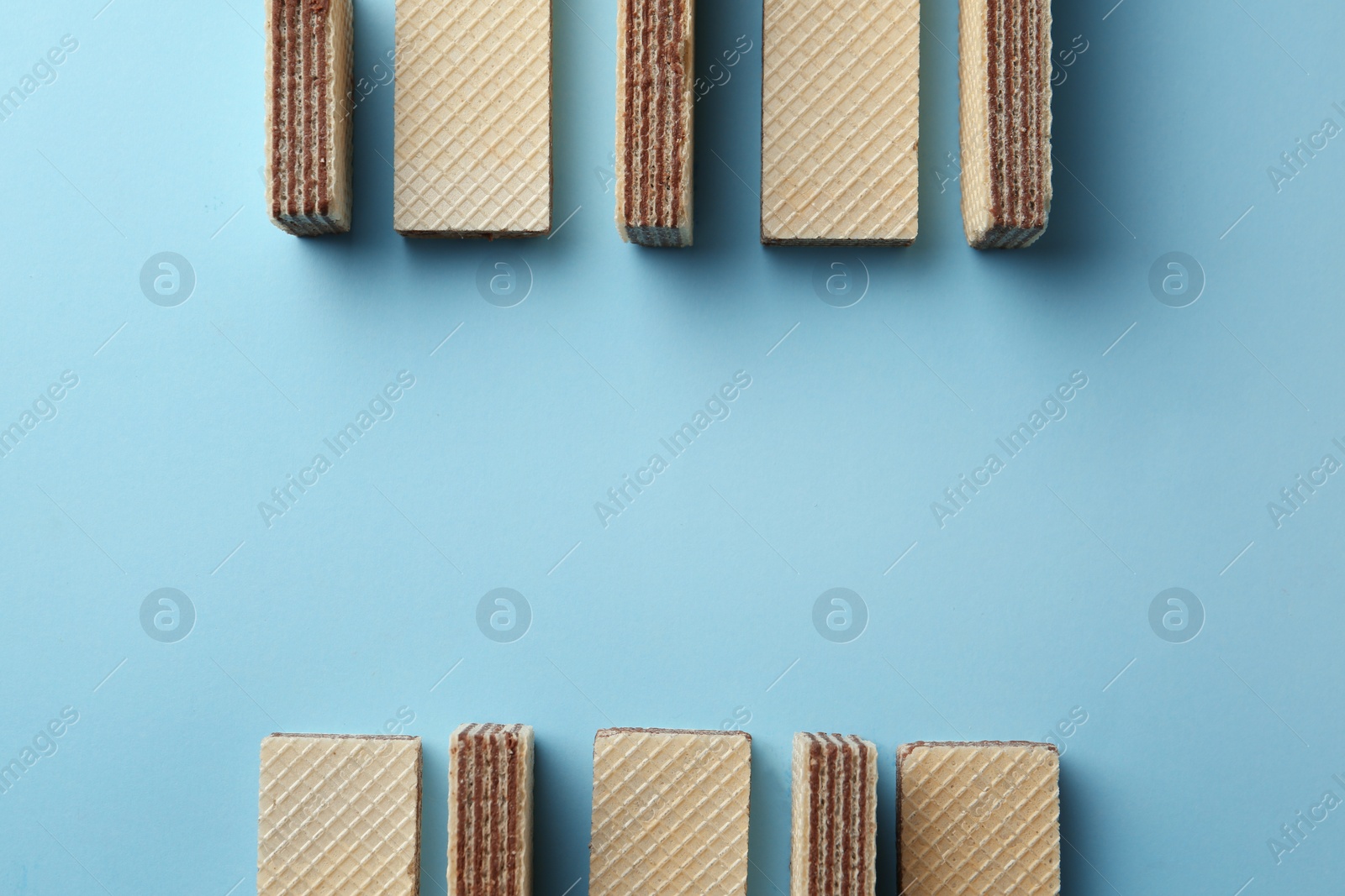 Photo of Tasty wafer sticks on blue background, flat lay with space for text. Sweet food