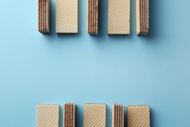 Tasty wafer sticks on blue background, flat lay with space for text. Sweet food