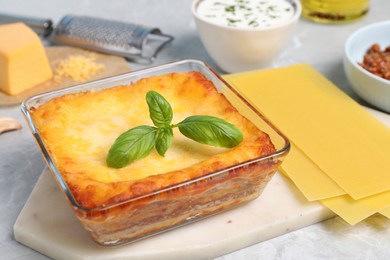 Photo of Tasty cooked lasagna in baking dish on light table
