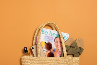 Photo of Flat lay composition with wicker bag and other beach accessories on orange background. Space for text