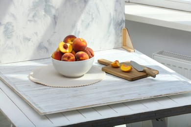 Photo of Bowl of juicy peaches and double-sided backdrop on table in photo studio