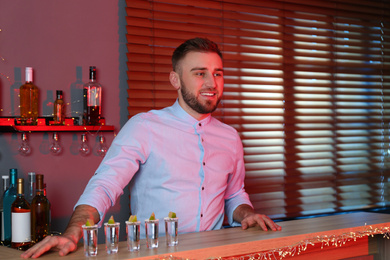 Bartender with shot glasses of Mexican Tequila at bar counter