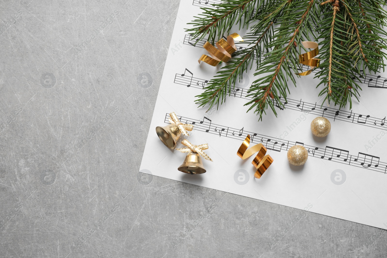 Photo of Christmas decorations and music sheet on grey stone table, flat lay with space for text