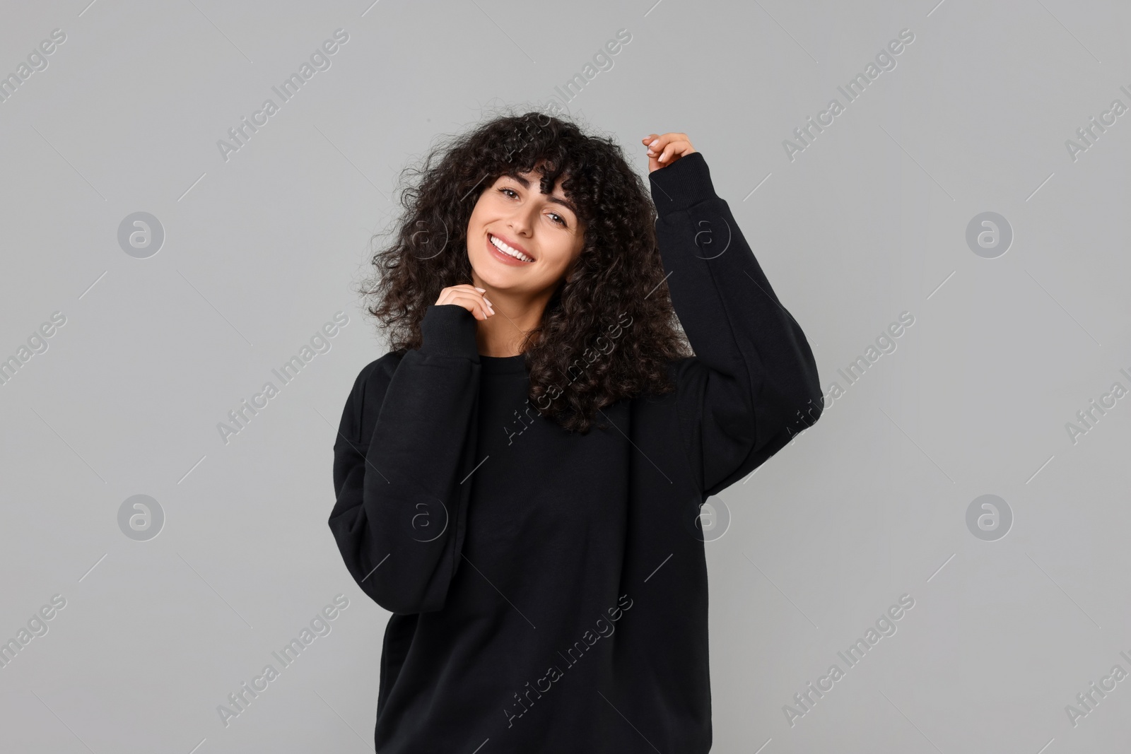 Photo of Happy young woman in stylish black sweater on light grey background