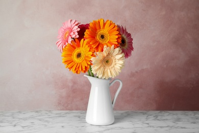 Photo of Bouquet of beautiful bright gerbera flowers in vase on marble table against color background