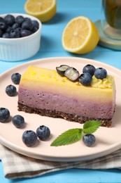 Photo of Delicious cheesecake with blueberry and mint on light blue wooden table