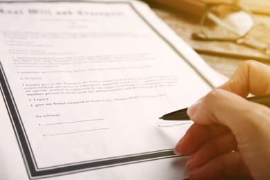 Image of Woman signing Last Will and Testament at table, closeup