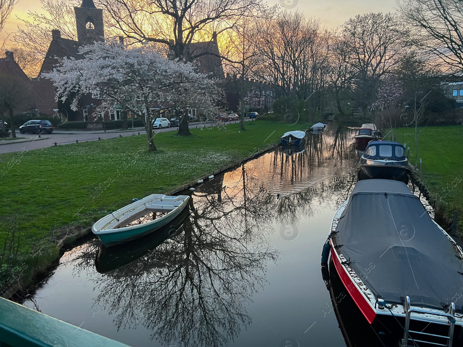 Photo of Canal with moored boats outdoors. Sky reflecting in water