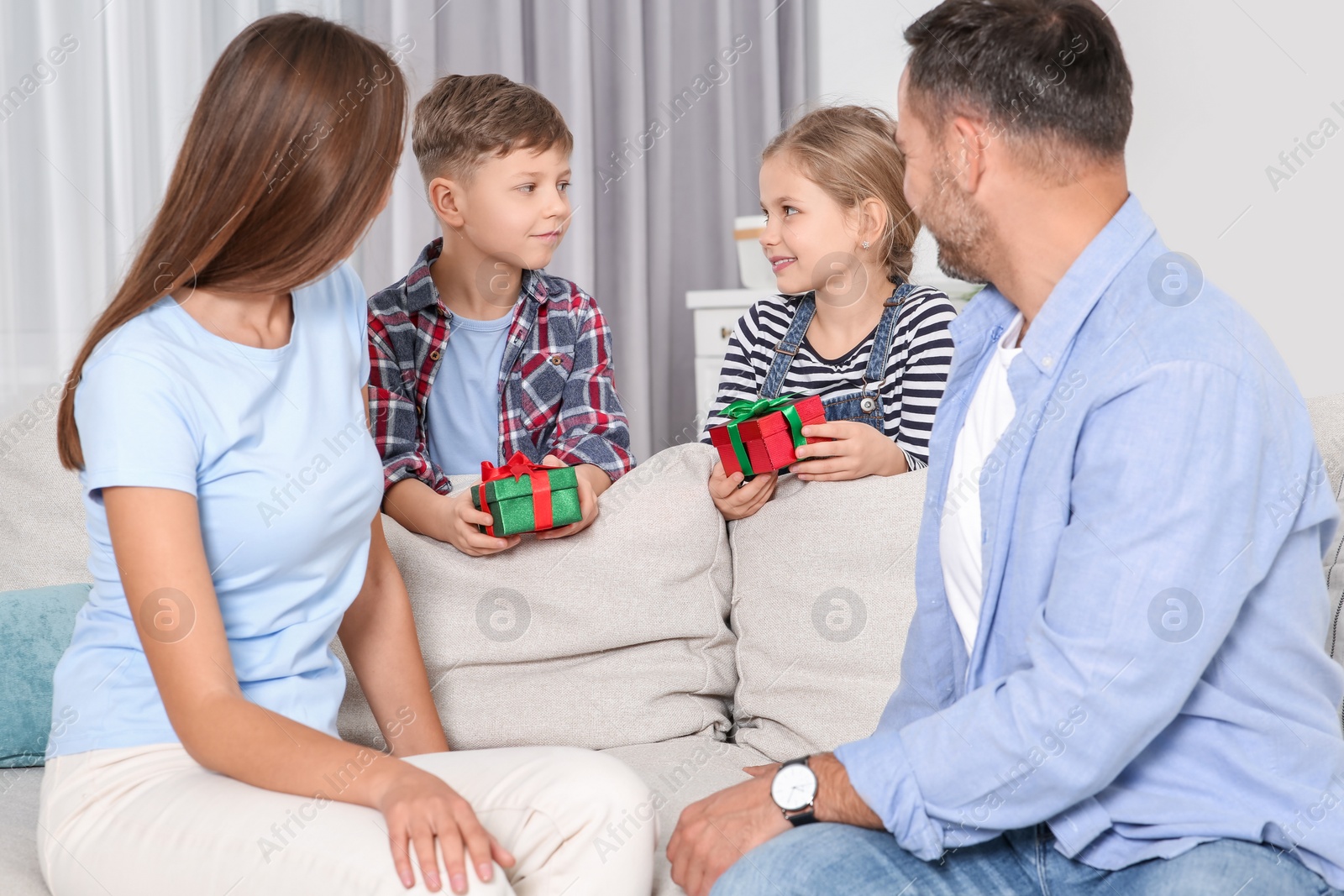 Photo of Little children presenting their parents with gifts at home