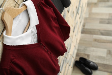 Photo of School uniform for girl hanging on brick wall, closeup