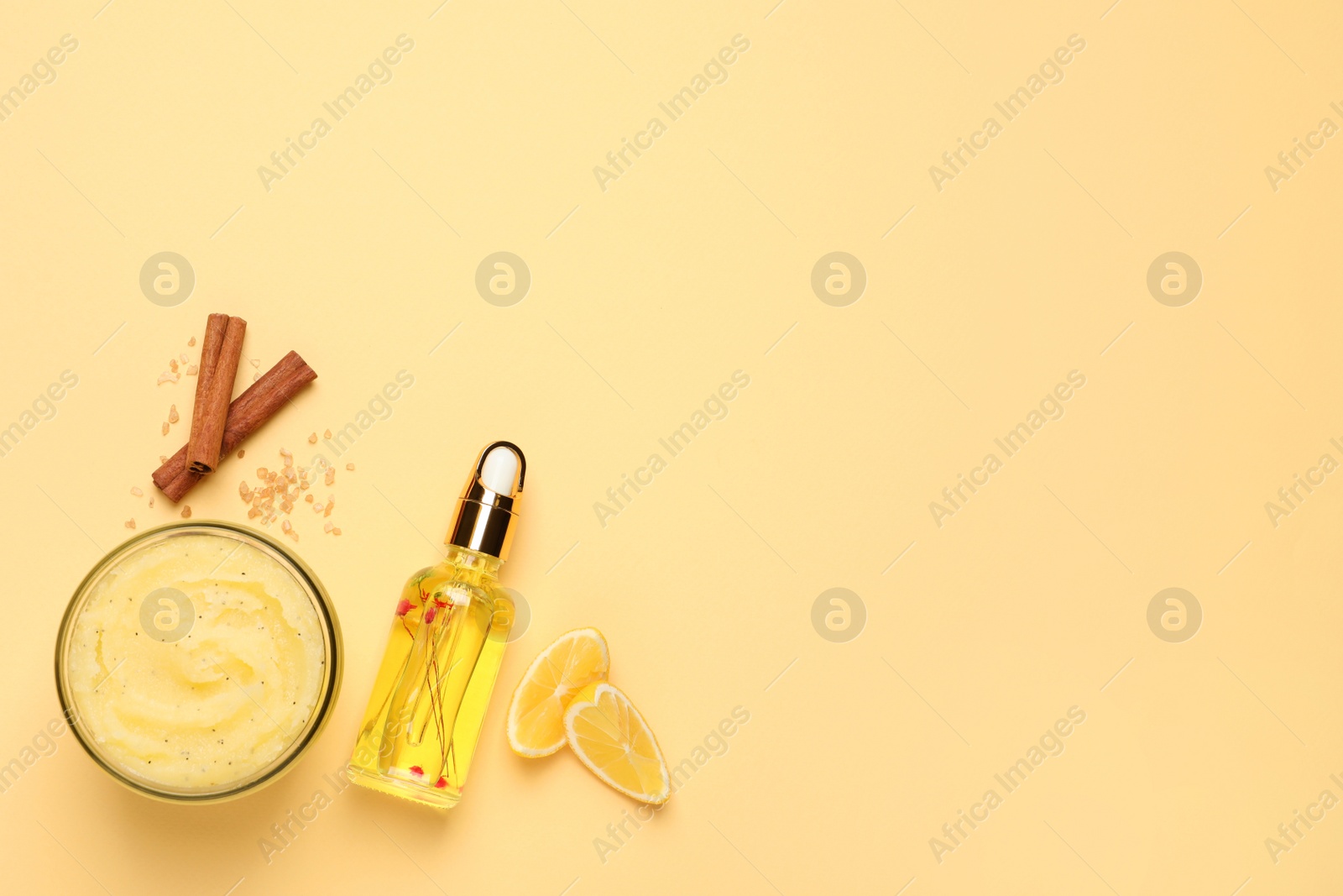 Photo of Body scrub in glass jar, oil, lemon and cinnamon on yellow background, flat lay. Space for text