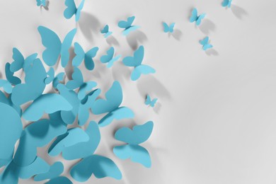 Light blue paper butterflies on white wall