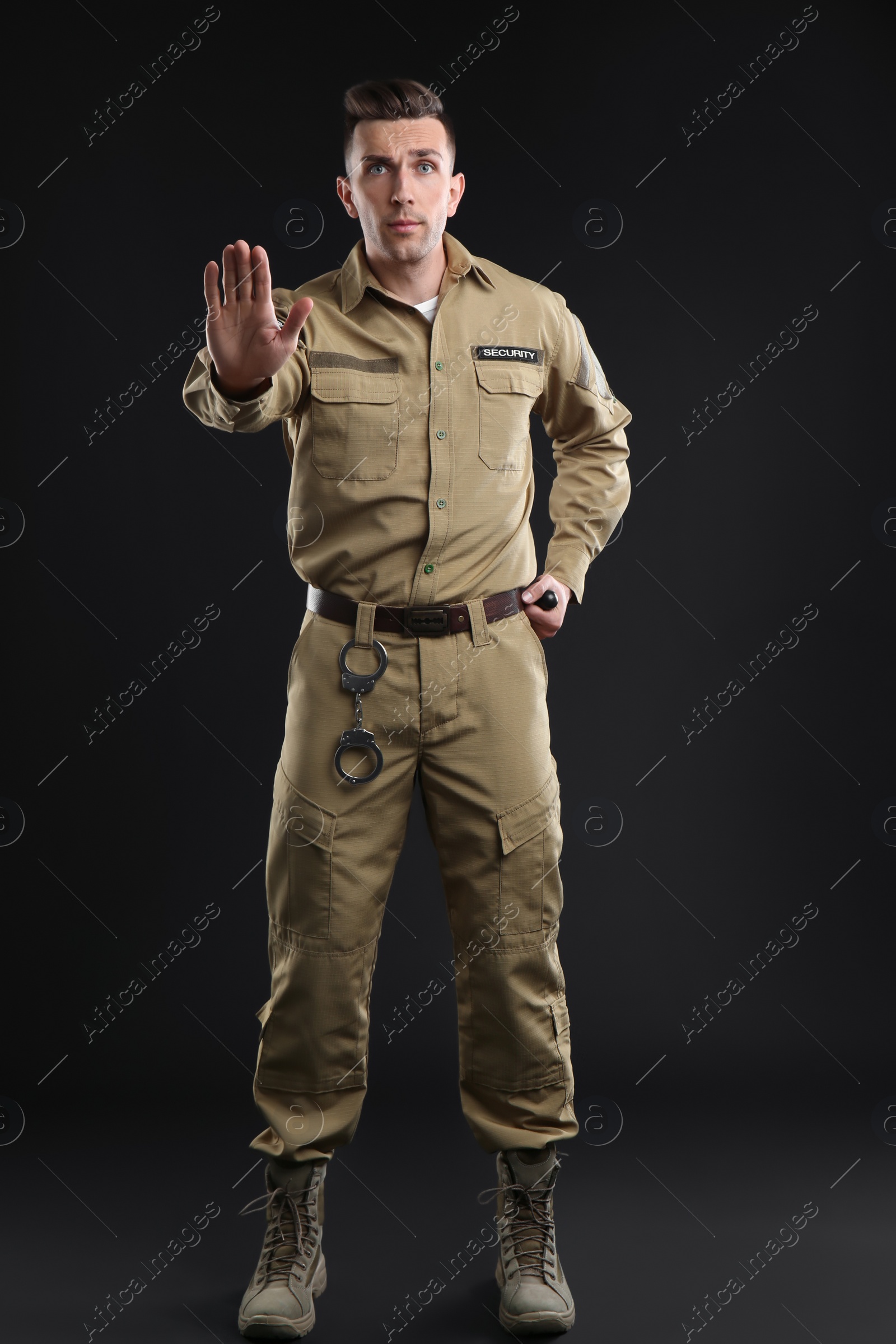 Photo of Male security guard with police baton on dark background