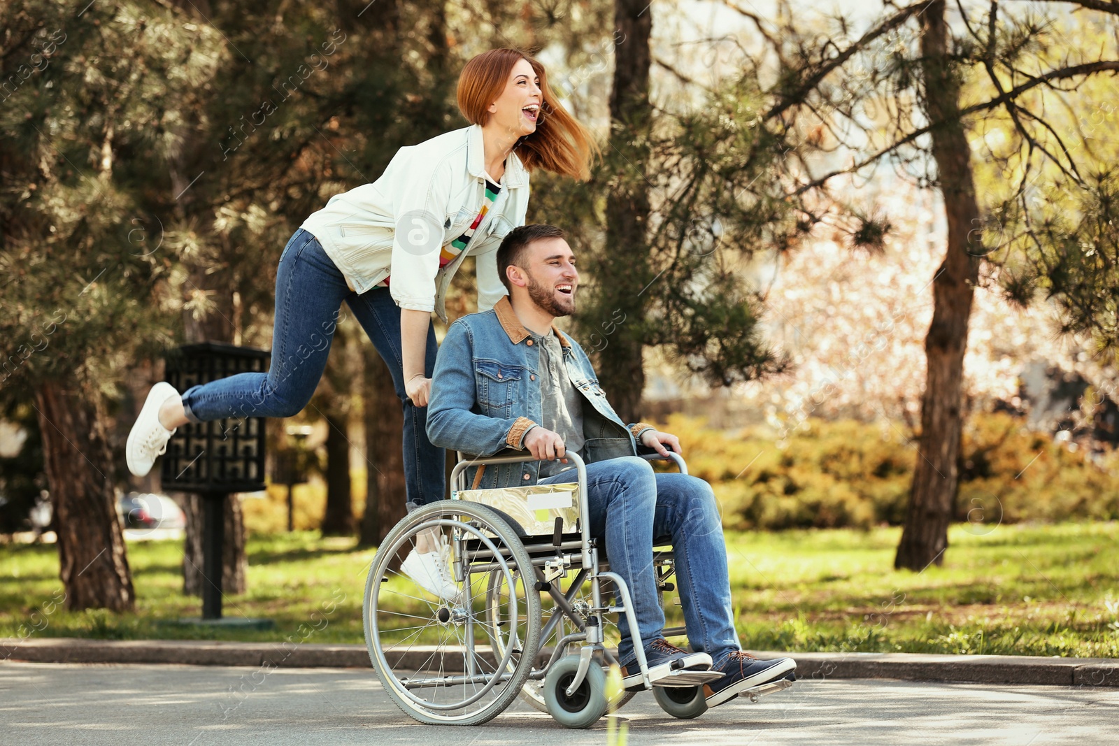 Photo of Young man in wheelchair and joyful woman at park