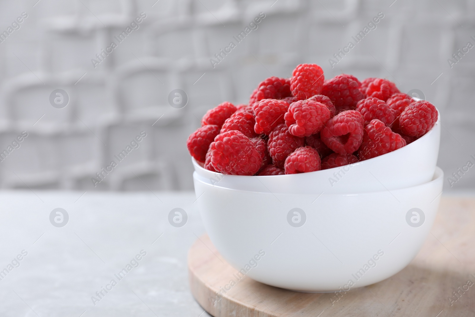 Photo of Delicious fresh ripe raspberries on grey table. Space for text