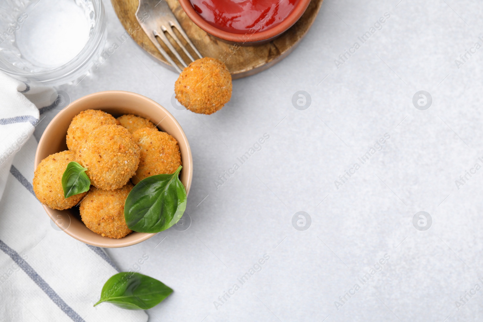 Photo of Bowl of delicious fried tofu balls with basil and ketchup on white table, flat lay. Space for text