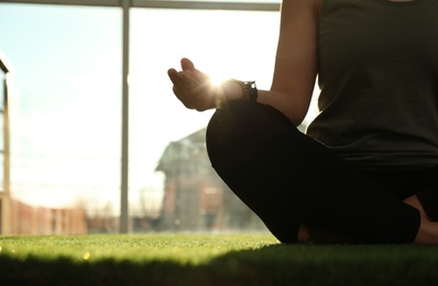 Photo of Young woman practicing yoga in sunlit room, closeup with space for text