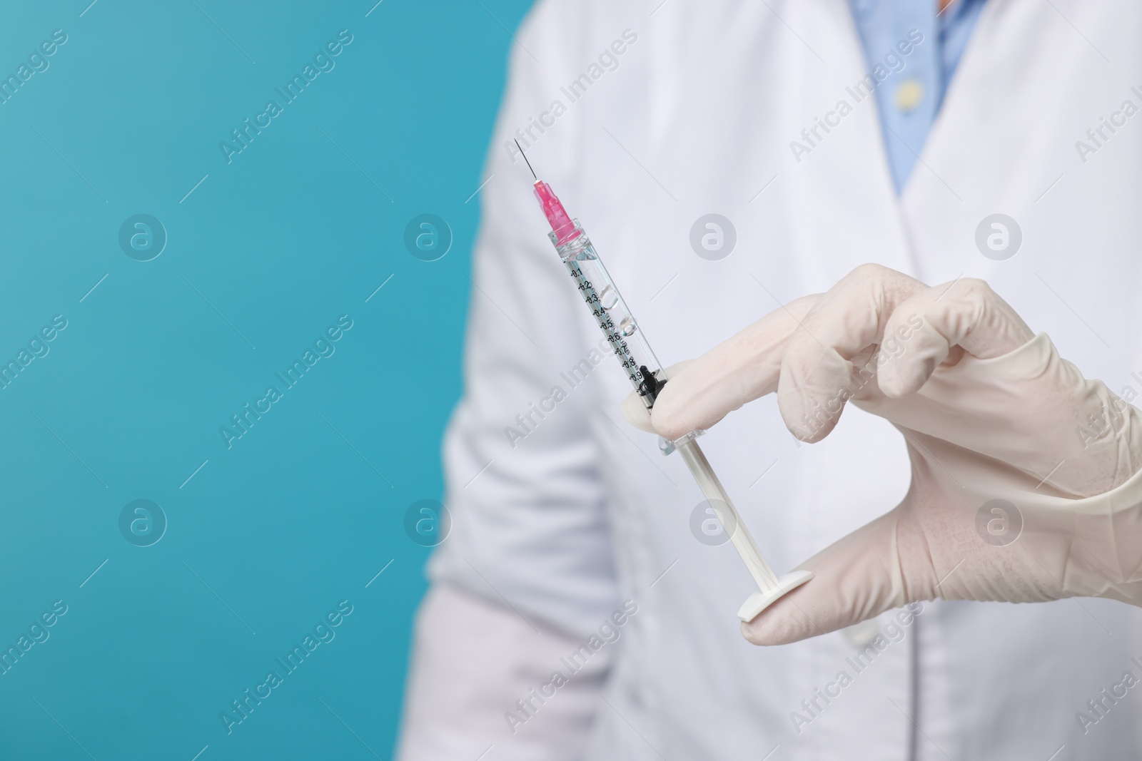 Photo of Doctor holding syringe on light blue background, closeup. Space for text