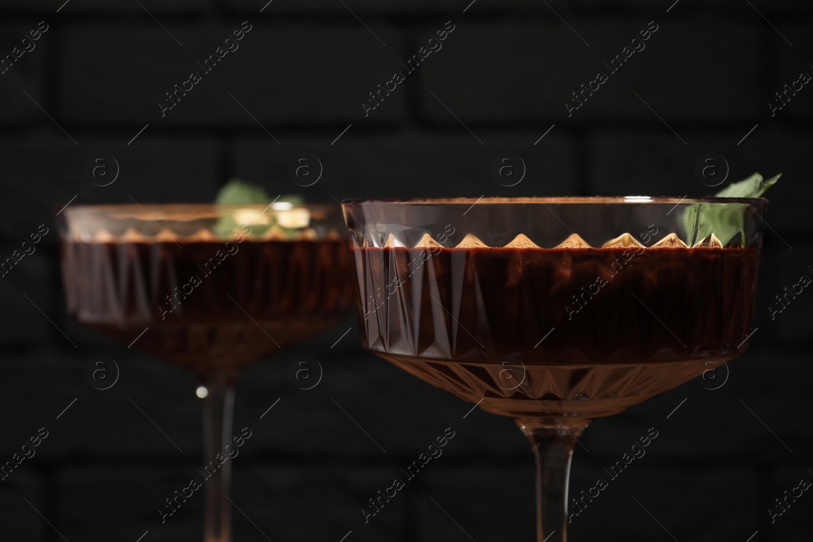 Photo of Dessert bowls of delicious hot chocolate with fresh mint on dark background, closeup