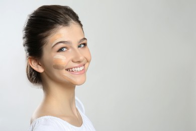 Photo of Beautiful girl on light grey background. Using concealers and foundation for face contouring