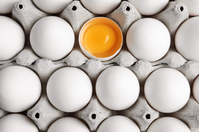 Many fresh raw chicken eggs in cartons as background, top view