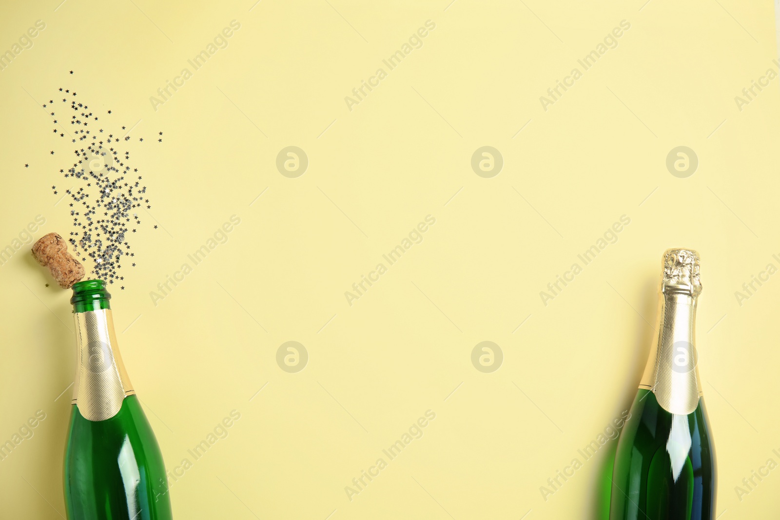 Photo of Creative flat lay composition with bottles of champagne and space for text on color background