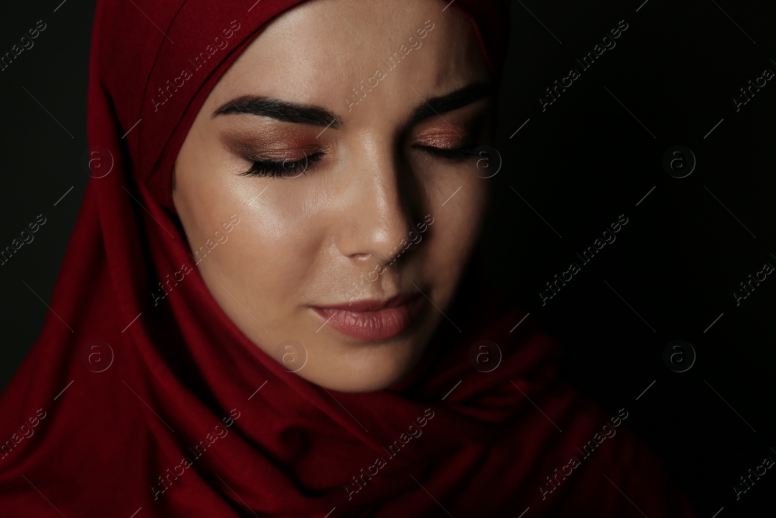 Photo of Portrait of sad Muslim woman in hijab on dark background