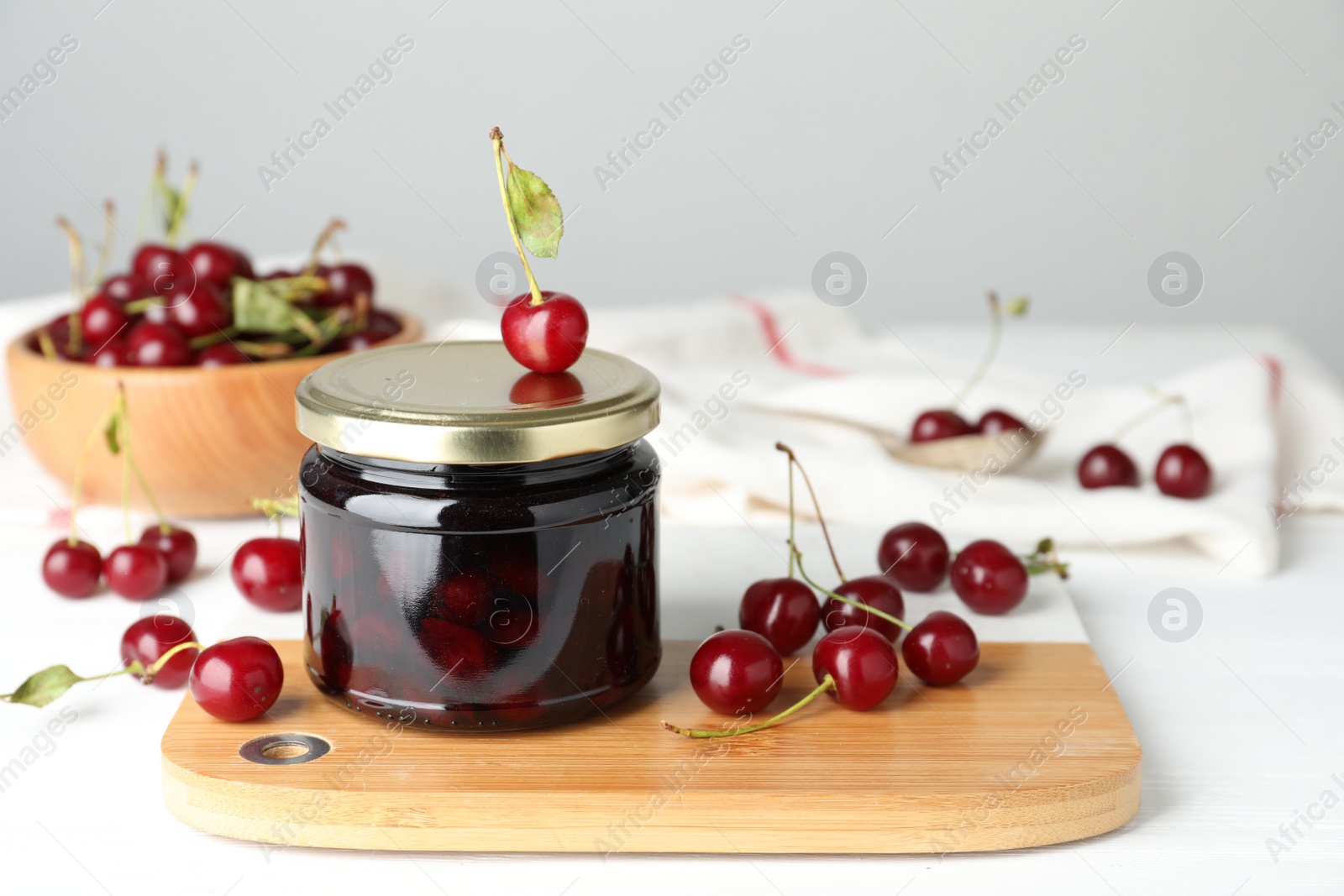 Photo of Jar of pickled cherries and fresh fruits on white table