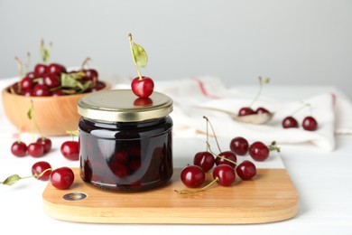 Photo of Jar of pickled cherries and fresh fruits on white table