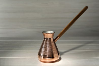 Photo of Beautiful copper turkish coffee pot on white wooden table