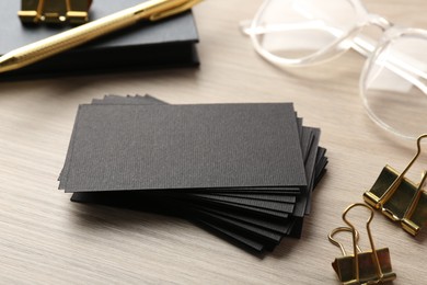 Photo of Blank black business cards and other stationery on wooden table, closeup. Mockup for design