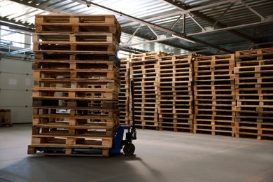 Modern manual forklift with wooden pallets in warehouse, space for text