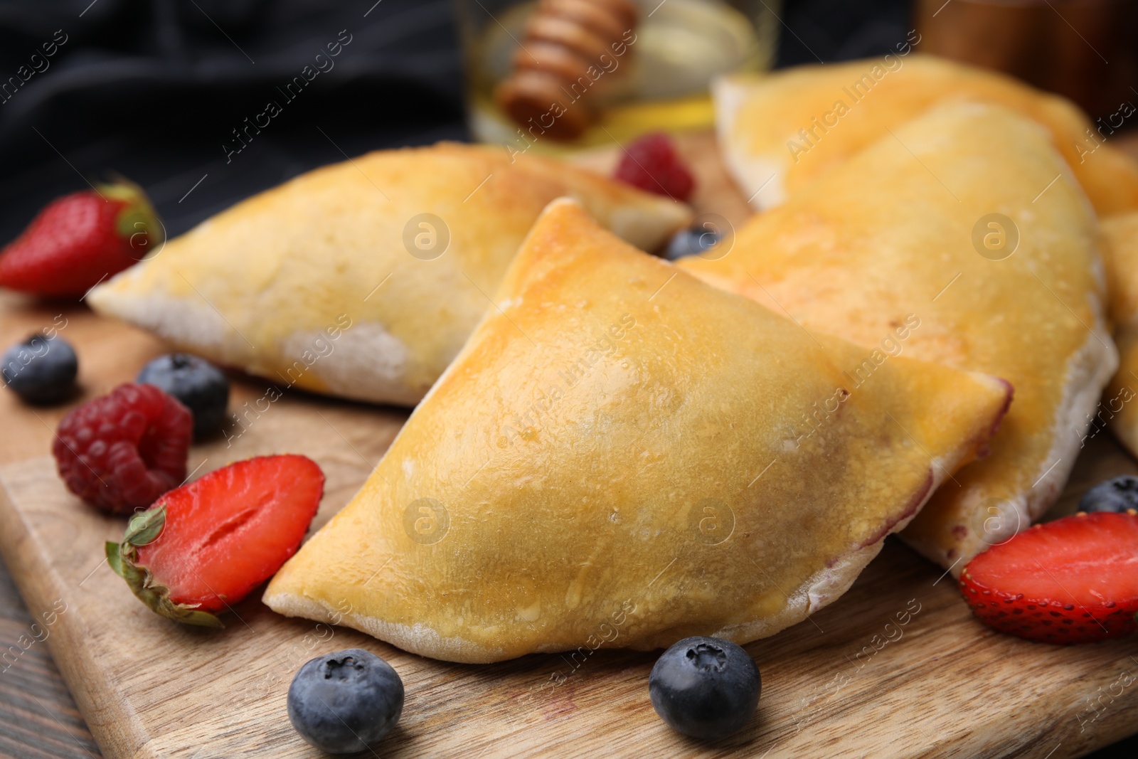 Photo of Delicious samosas and berries on wooden board, closeup