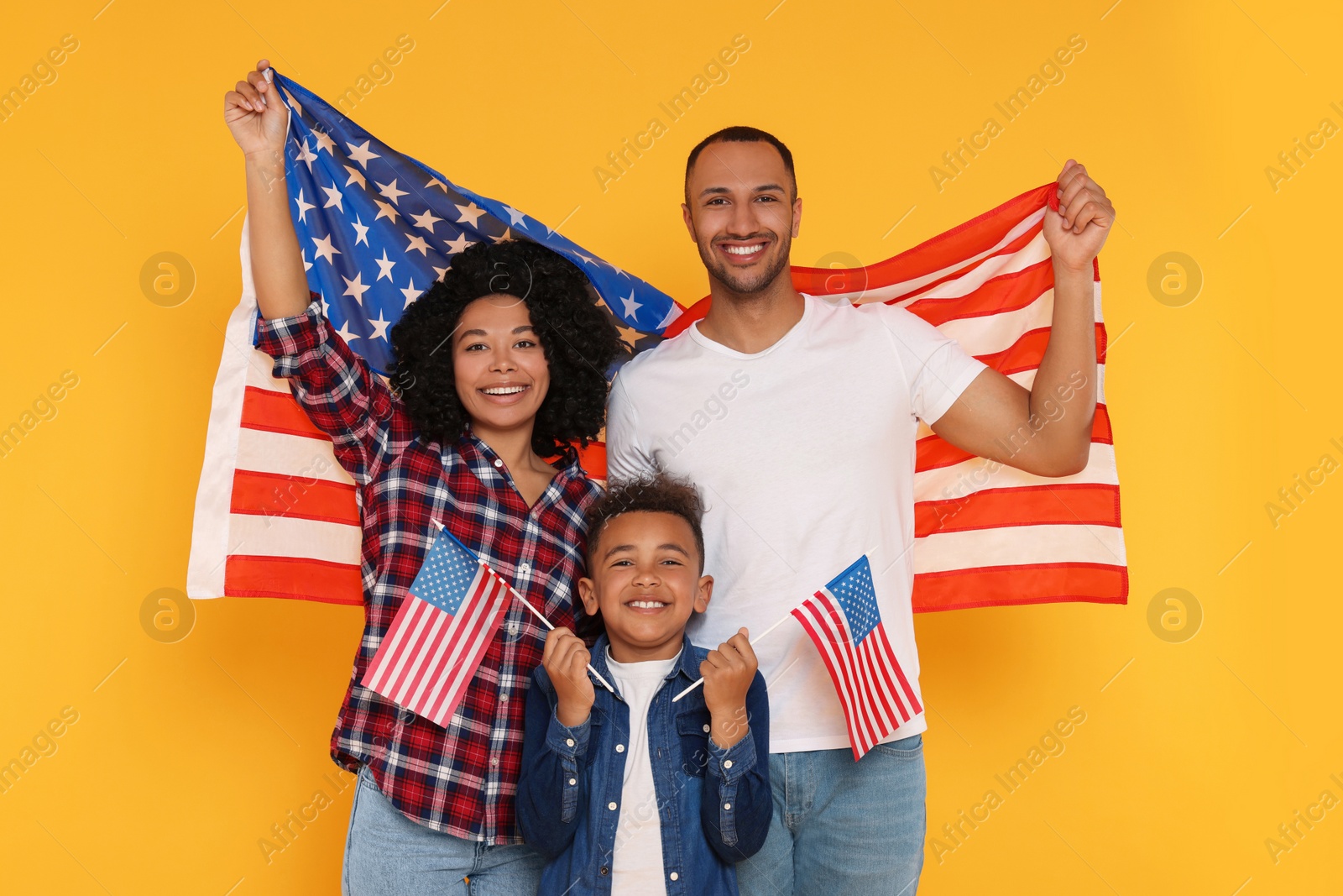 Photo of 4th of July - Independence Day of USA. Happy family with American flags on yellow background