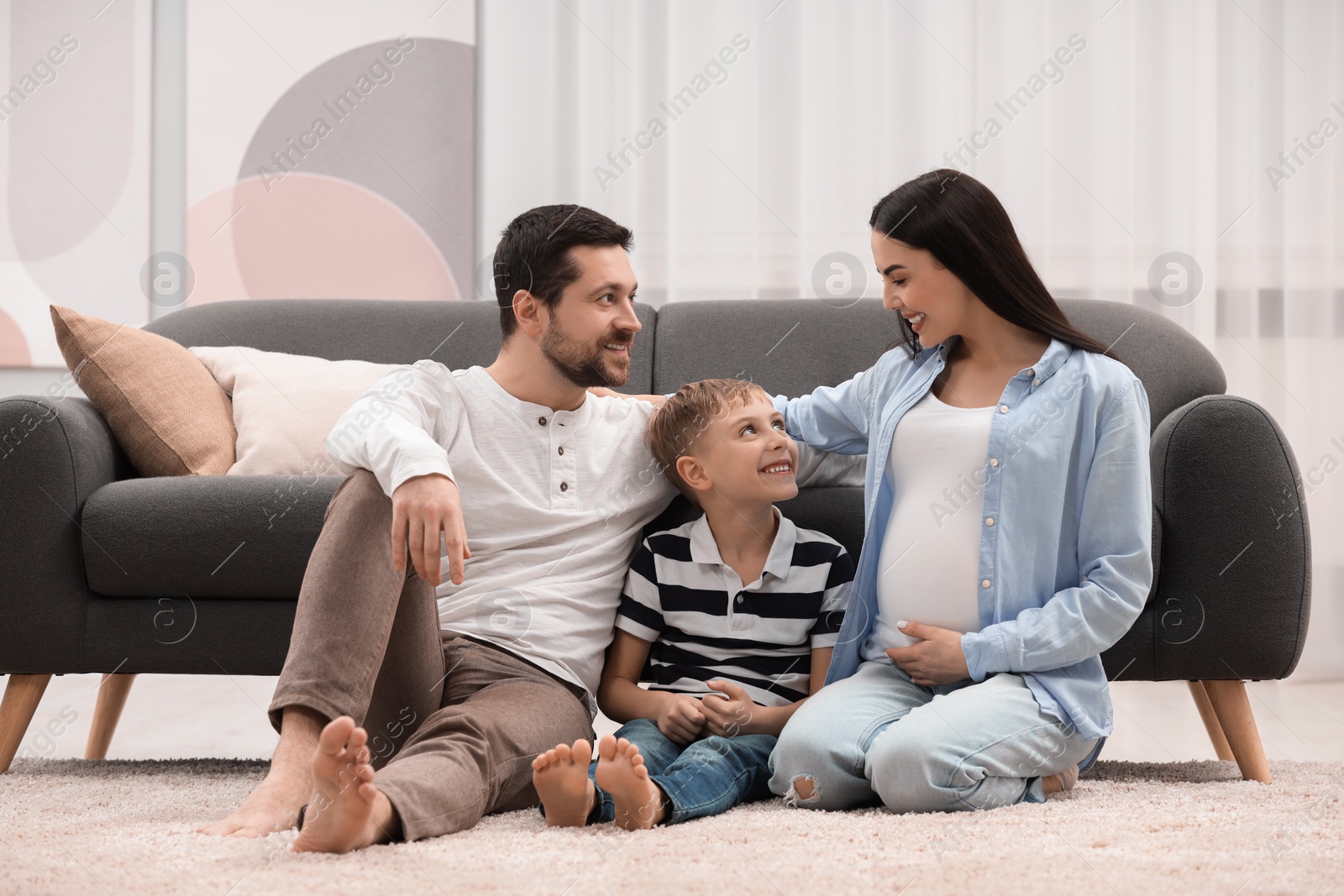 Photo of Pregnant woman spending time with her son and husband at home. Happy family