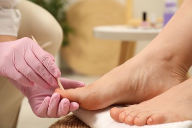 Photo of Professional pedicurist working with client`s toenails in beauty salon, closeup