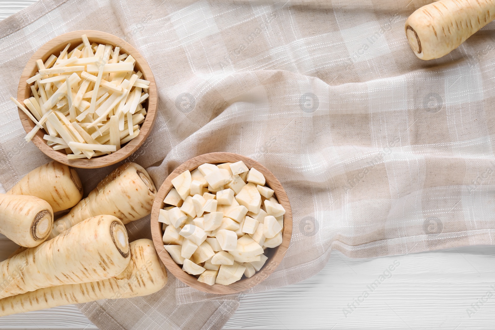 Photo of Whole and cut parsnips on white wooden table, flat lay. Space for text