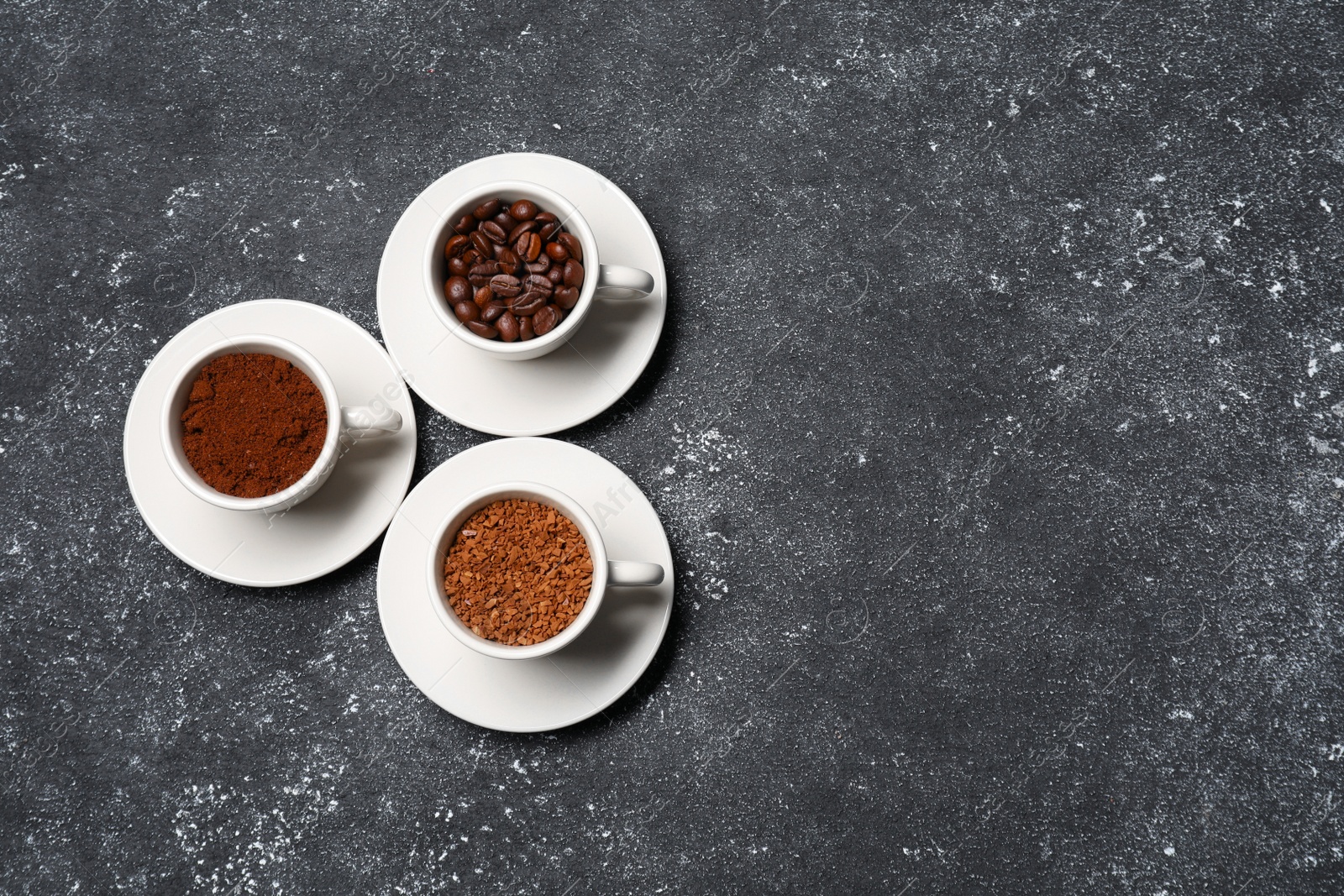 Photo of Cups with different types of coffee on dark grey table, flat lay. Space for text